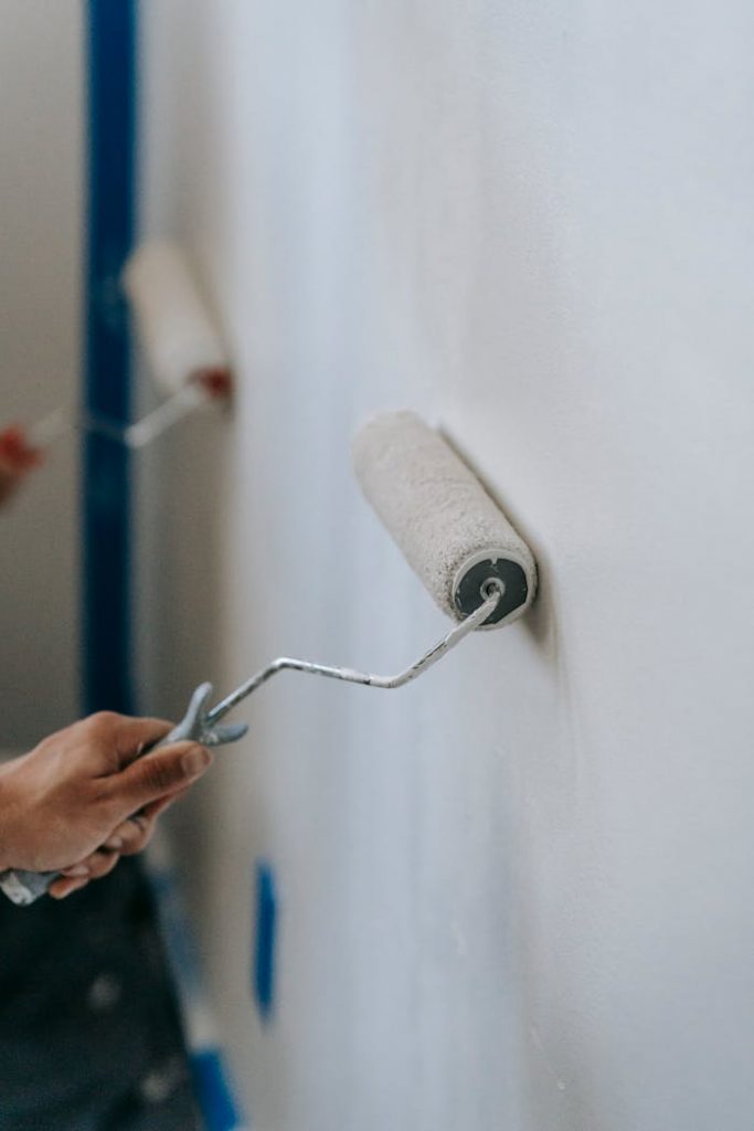 pexels photo 7218011 Close-up of hands using paint rollers to renovate an interior wall of a home.
